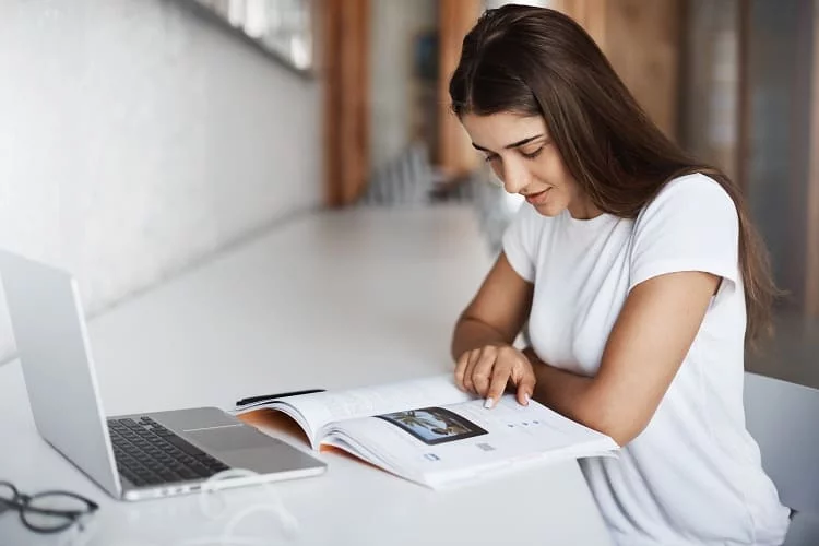 Student learning English with a book and laptop